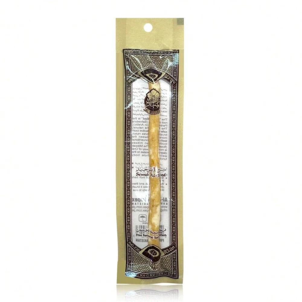 A traditional wooden miswak toothbrush packaged in a clear plastic pouch with decorative elements.