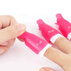 Una mano sostiene una pinza reutilizable de plástico rosa para remojar uñas con puntas blancas.