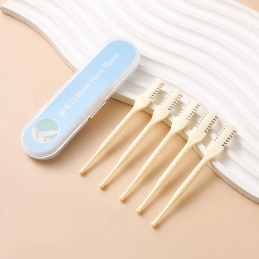 A clear plastic case holds several light-colored double-sided nose hair razors resting on a beige surface.