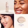 Close-up of a woman applying a light liquid lumizier on her face.