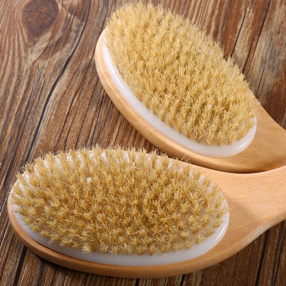 A natural wooden body brush with golden bristles is shown on a wooden surface.