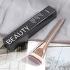 A black and silver packaging box for a premium beauty brush with a gold-toned flat kabuki brush visible.