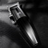 A black professional electric hair trimmer kit lying on a dark textured surface.