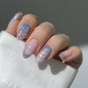 A hand displaying 24 pink flower almond press on nails with a shimmering iridescent finish.