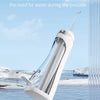 A white portable oral irrigator device is shown being used to rinse the mouth, with water flowing from a glass tube.