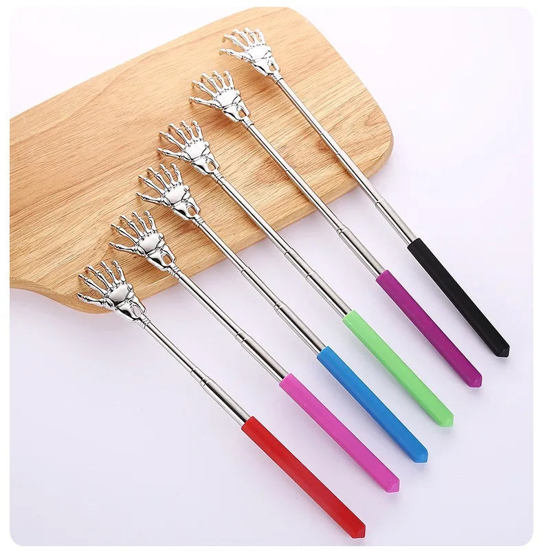 A set of telescoping stainless steel back massagers with silver tips and colored handles resting on a wooden board.