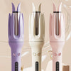 Three automatic hair curlers in purple, white, and pink are displayed on a cake.