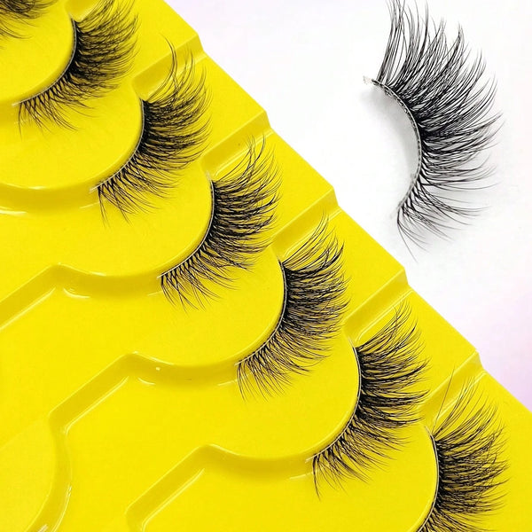 A close-up of yellow false eyelashes with long, wispy black lashes displayed on a white background.