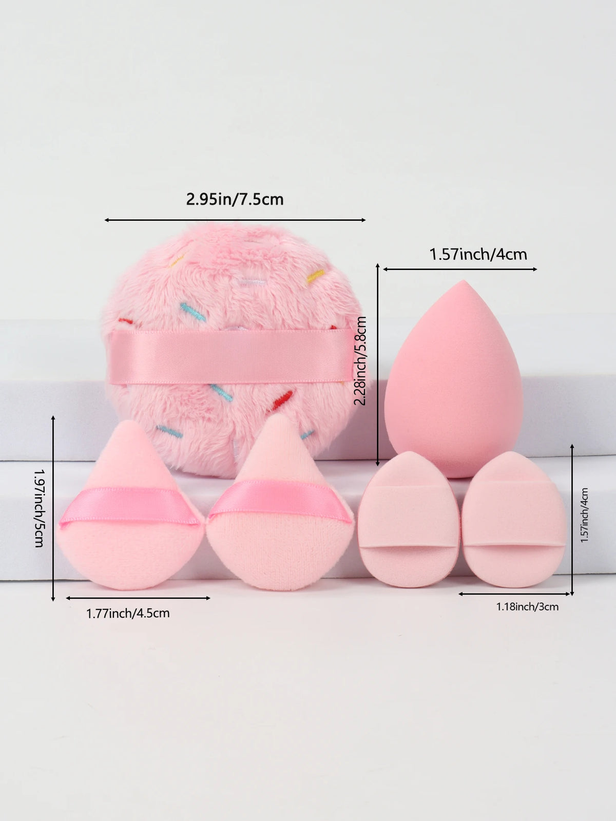 Un set de poudre de couleur rose, comprenant une grande boule duveteuse et plusieurs formes coniques.