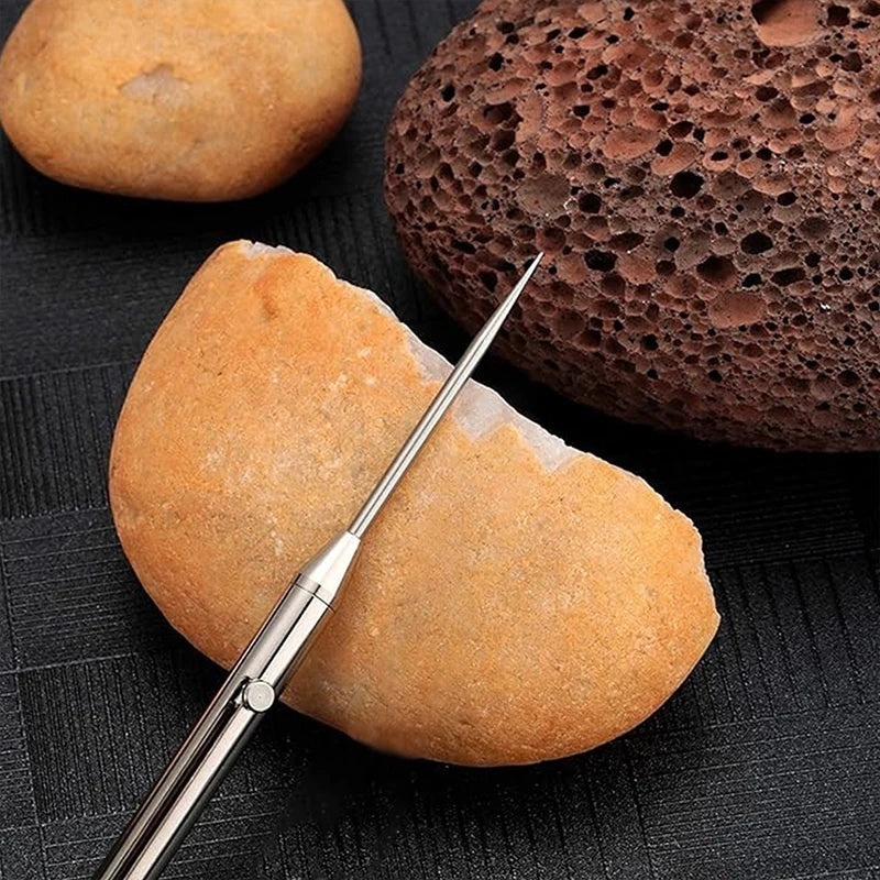 A titanium keychain toothpick set with a pointed tip resting on a light brown food item next to a dark brown porous object.