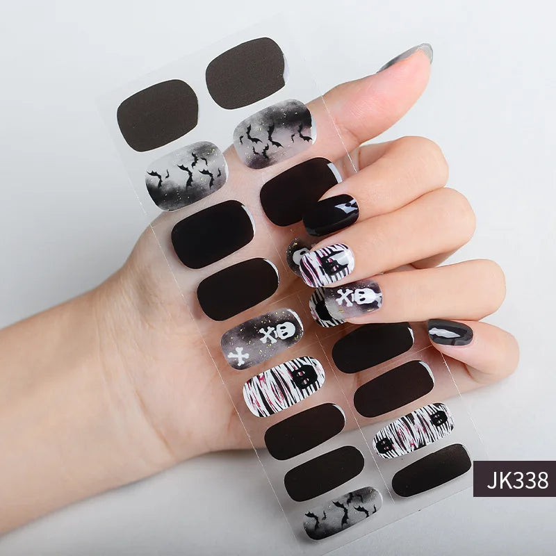 A hand displays a set of Halloween UV gel nail stickers featuring black and white marbled designs on clear adhesive sheets.