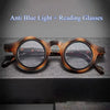 Une paire de lunettes de lecture à monture marron avec des verres clairs posées sur une surface sombre.