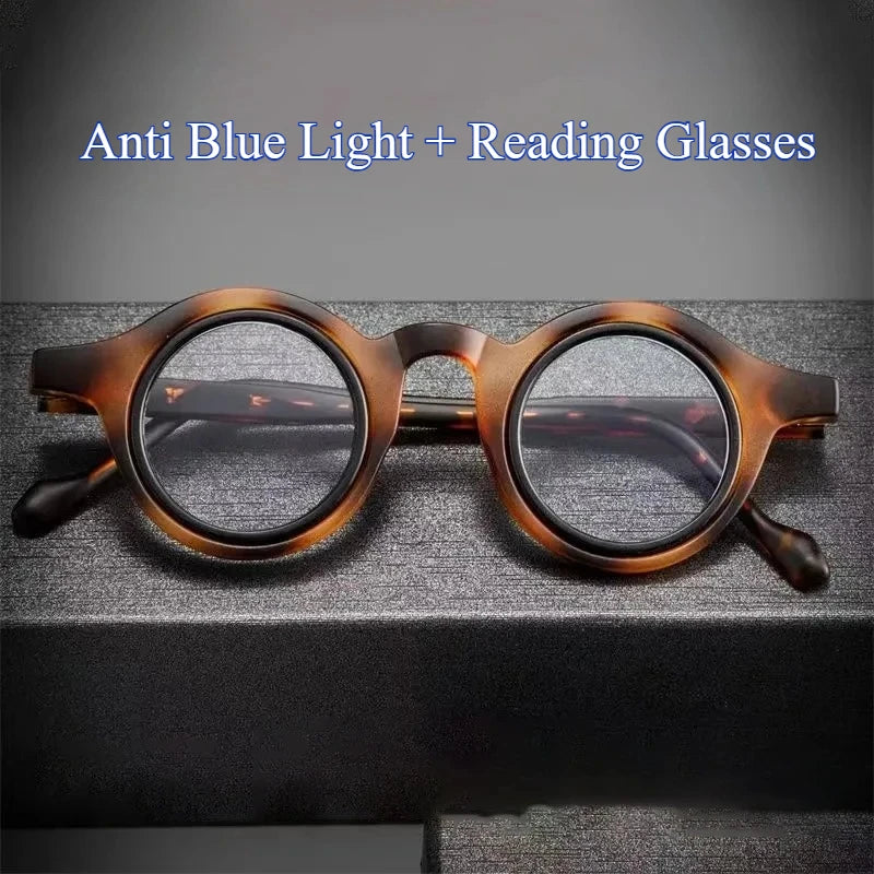 Une paire de lunettes de lecture à monture marron avec des verres clairs posées sur une surface sombre.