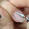 A hand holds a tungsten carbide nail drill bit, showing the tip used for precision manicure or pedicure work.
