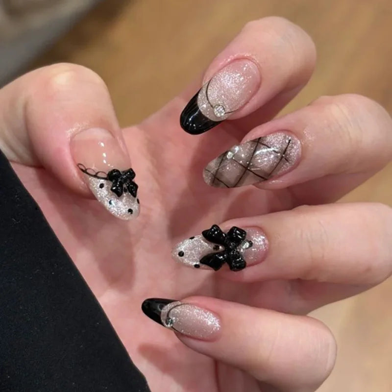 Une main montre un ensemble de faux ongles à almonds roses français avec paillettes et accents noirs.