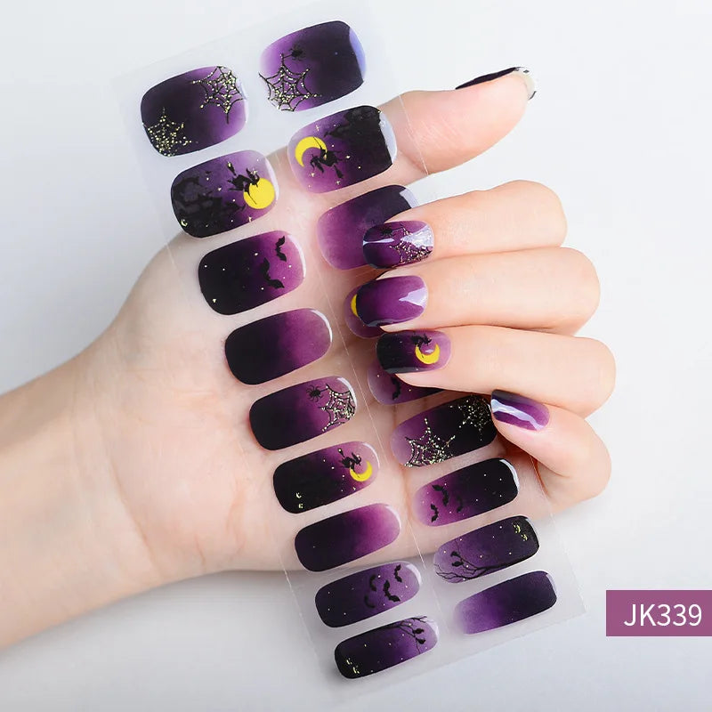 A hand displays Halloween UV gel nail stickers featuring purple and black designs with glitter accents.