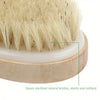 Primer plano de un cepillo exfoliante natural con cerdas beige claras sobre una base de madera.