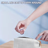 A hand is holding a small clear plastic eyelash curler set above a light-colored zippered pouch.