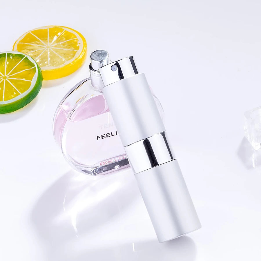 Flacon d'eau de parfum argenté à côté d'une tranche de citron jaune et d'un quartier de lime.