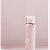 A pink electric razor bottle with a pump dispenser sits on a marble surface.