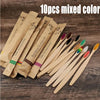 Ten pieces of mixed color eco-friendly bamboo toothbrushes displayed on a wooden surface.