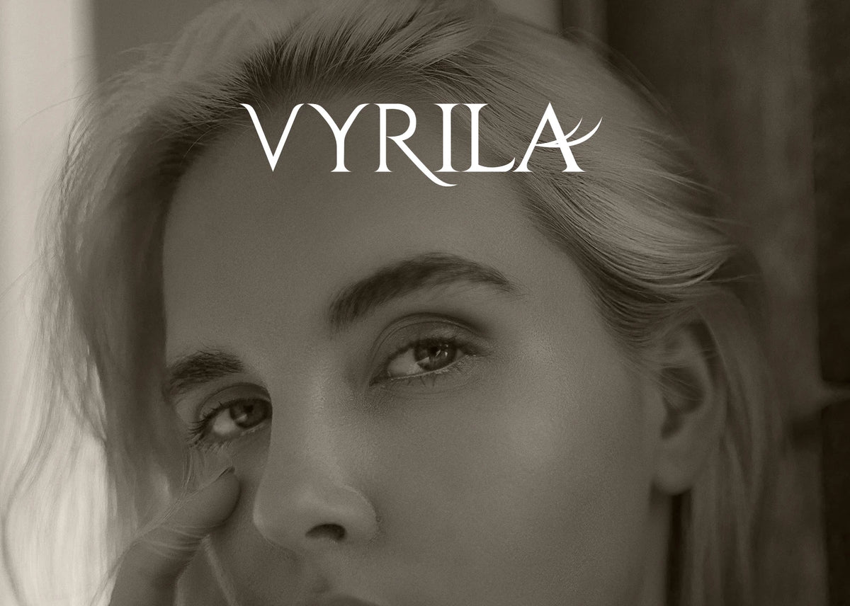 Close-up portrait of a woman with wispy eyelashes and the word VYRILA visible above her eyes.