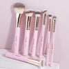 A set of seven pink and gold makeup brushes displayed on a white surface.