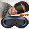 A pair of black 3D full shading sleep masks are shown resting on a white pillow.