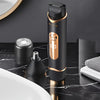 A black electric body hair trimmer with a gold accent is shown on a dark marble surface.