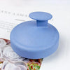 A smooth, light blue silicone scalp massage brush with a rounded top is shown on a white surface.