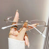 Eine Hand hält eine klare, frameless-Lesebrille mit Diamantverzierung und zeigt das Brillendesign.