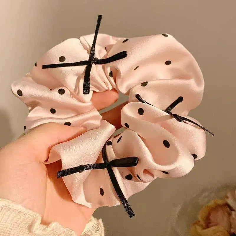 Scrunchies en satin à pois roses attachées avec un élastique noir