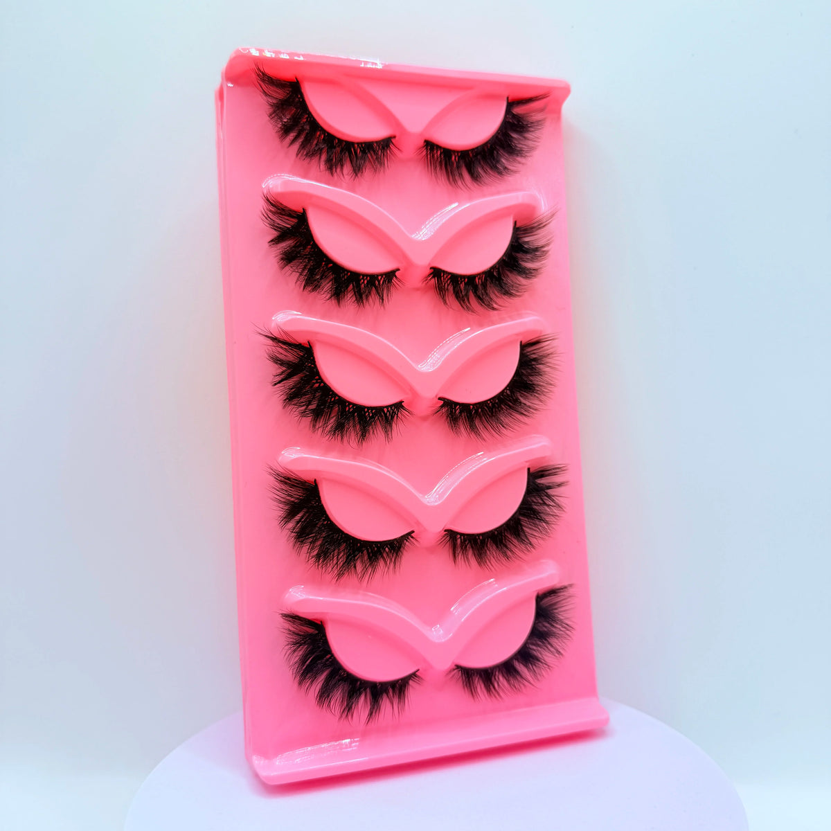 Plateau en plastique rose contenant cinq paires de faux cils dramatiques.