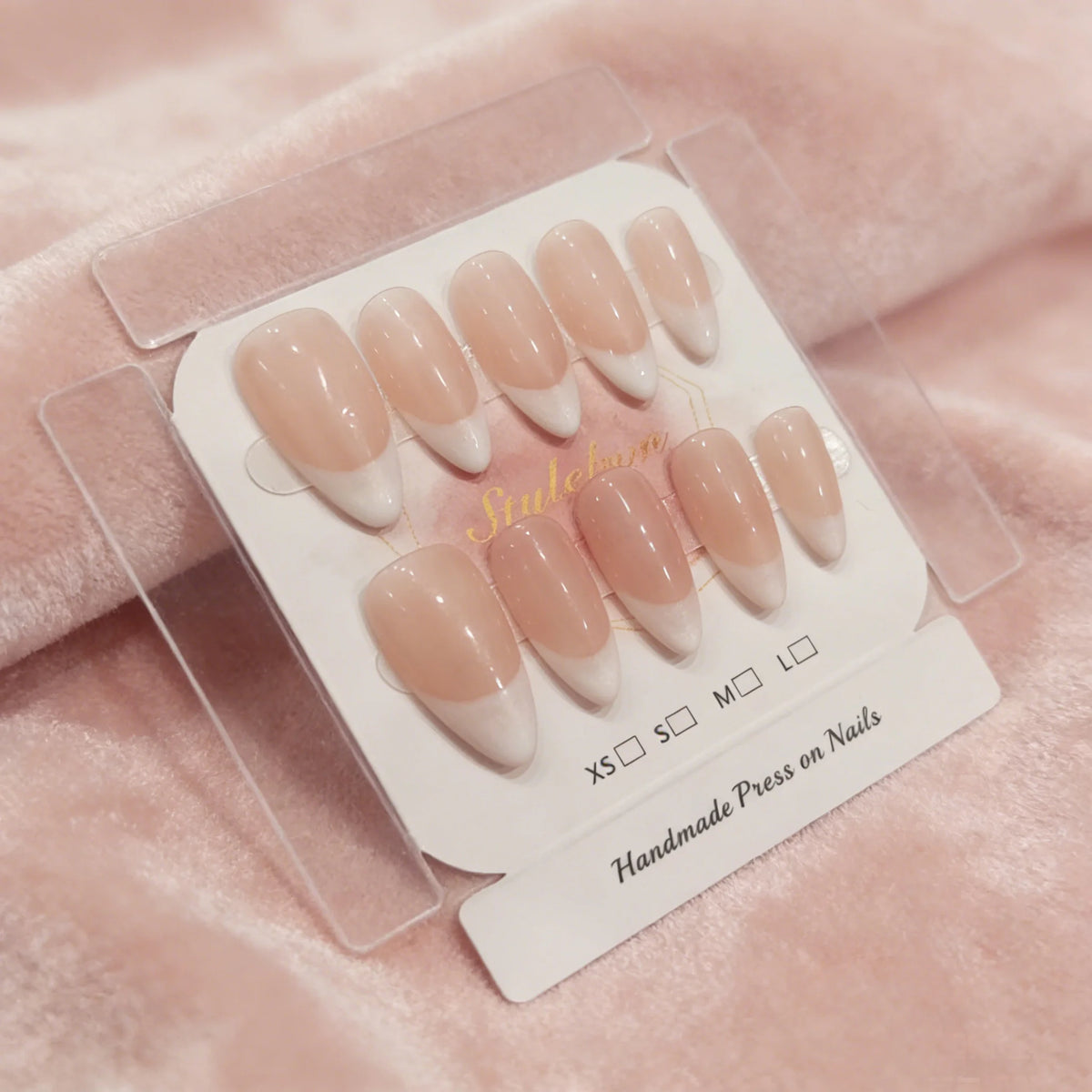 A set of pink handmade press-on nails with a French almond shape displayed on a clear card.