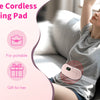 A woman is using a portable cordless heating pad massage belt on her torso while relaxing on a couch.