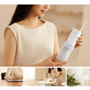A woman is using a white portable cordless oral irrigator device for cleaning.