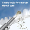 A close-up of an ultrasonic electric dental cleaner device and a dental mirror with cleaning particles.