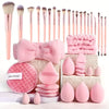 A collection of pink makeup brushes, sponges, and applicators arranged on a white surface.