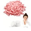A pile of pink disposable wet wipes next to a woman applying wipes to her face.