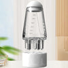 A clear glass portable scalp applicator with measurement markings sits on a white base.