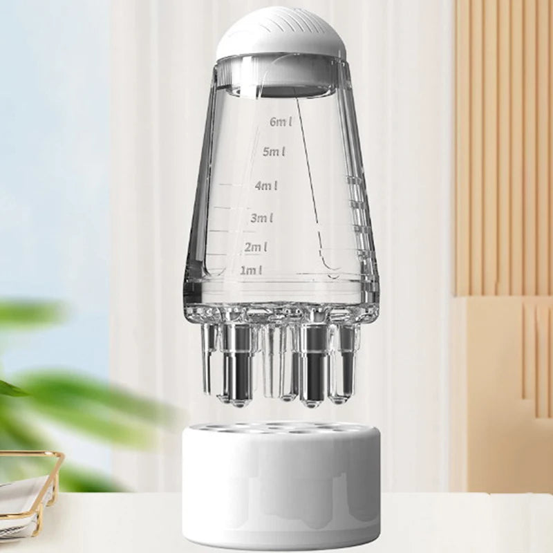 A clear glass portable scalp applicator with measurement markings sits on a white base.