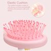 A pink silicone massage comb with numerous bristles is shown in a close-up view.