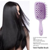 A purple vent paddle brush for detangling hair is shown next to a woman's long black hair.