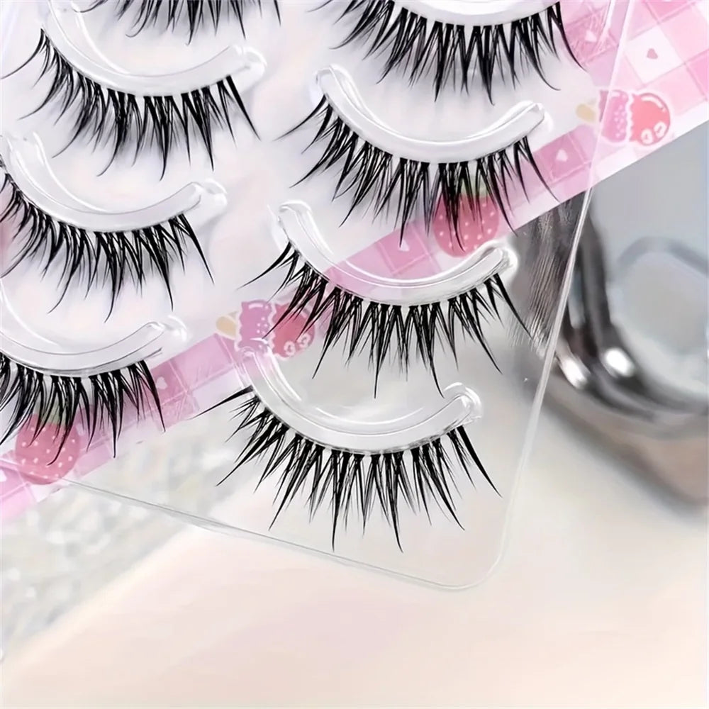 Five pairs of natural cat eye and C-roll strip false eyelashes displayed on a clear plastic sheet.