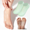Ein Paar hellgrüner Silikon-Fußsocken, die auf einem Fuß getragen werden, mit Nahaufnahme der nackten Füße darunter.
