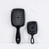 A black detangling hair comb with a wide, rounded end and a serrated comb on a white background.