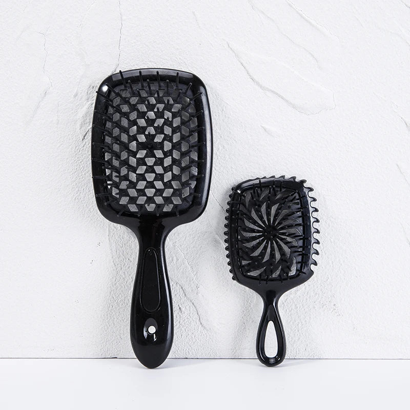 A black detangling hair comb with a wide, rounded end and a serrated comb on a white background.