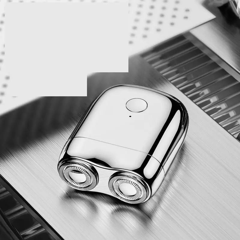 A close-up, silver mini electric beard trimmer shaver resting on a dark surface.