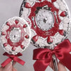 A hand is holding a decorative makeup mirror set featuring red and white accents and a satin ribbon.