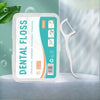 A white container of dental flossers with a green and teal label and a white plastic tool is displayed on a light surface.